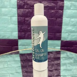 A white bottle of Salon Shampoo with a blue label on a glass surface.