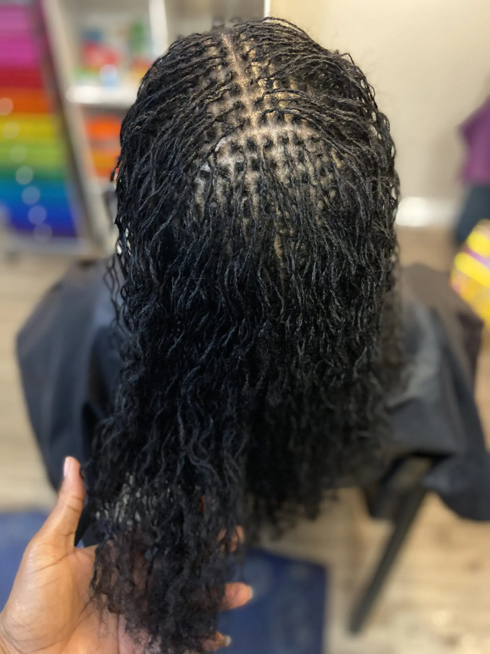 Close-up of a hair weaving pattern with curly hair attached.