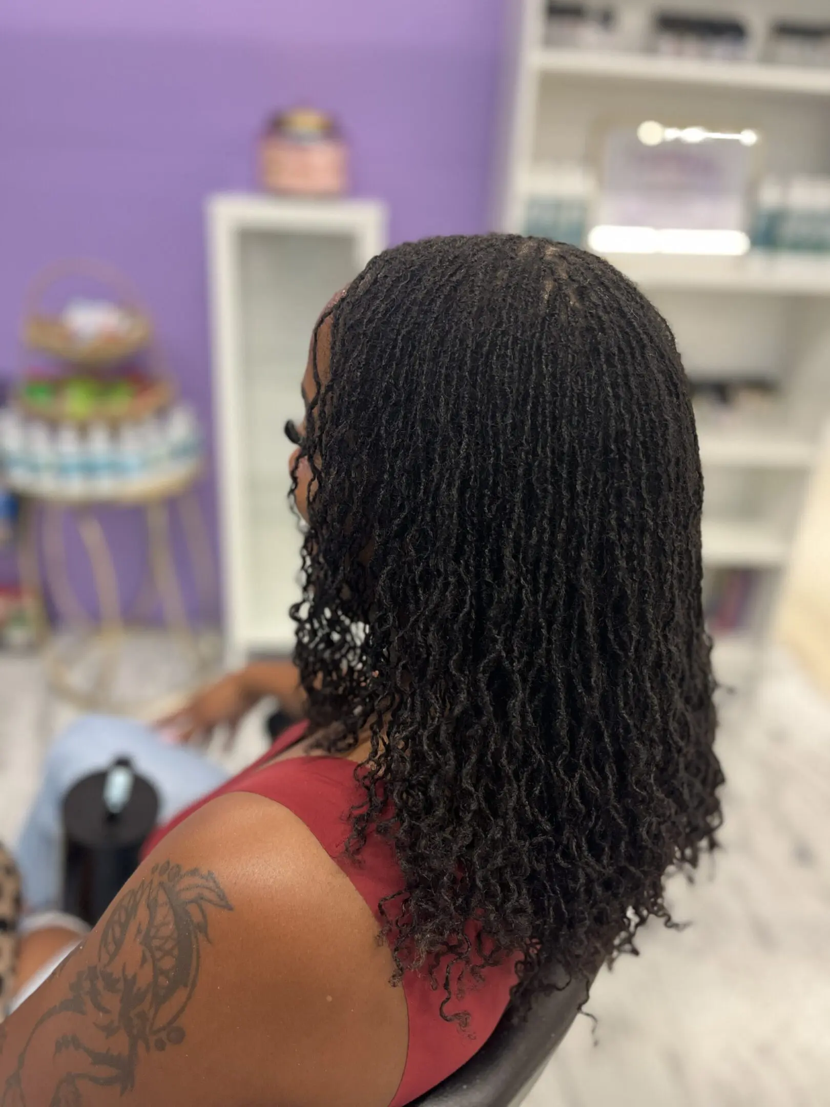 Person with fresh, curly black hair sitting indoors.