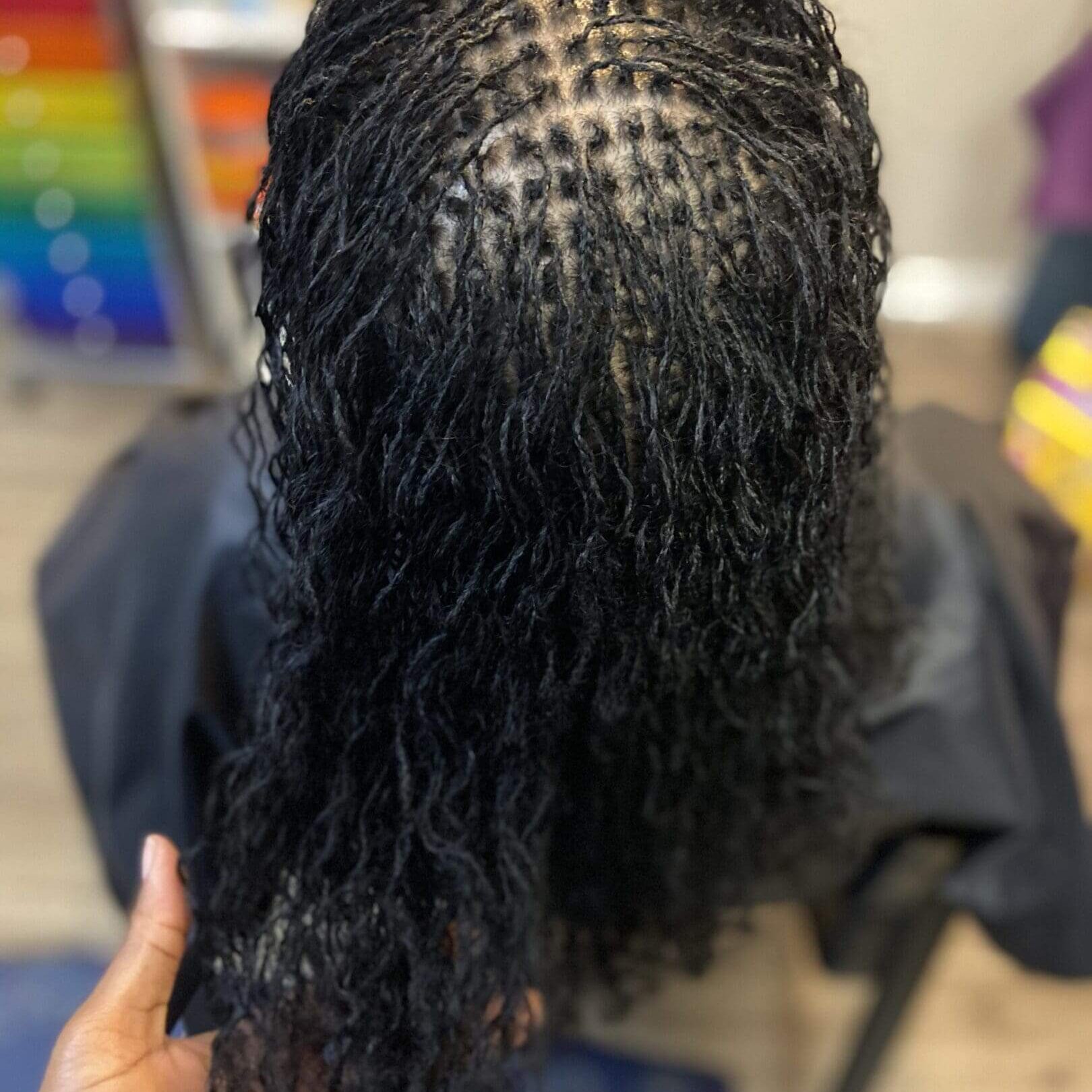 Close-up of a hair weaving pattern with curly hair attached.